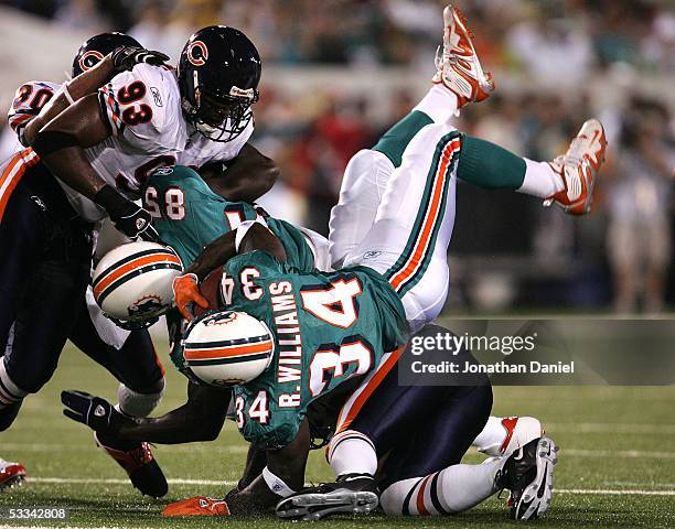 Running back Ricky Williams of the Miami Dolphins is upended by linebacker Lance Briggs of the Chicago Bears during the NFL Hall of Fame pre-season...