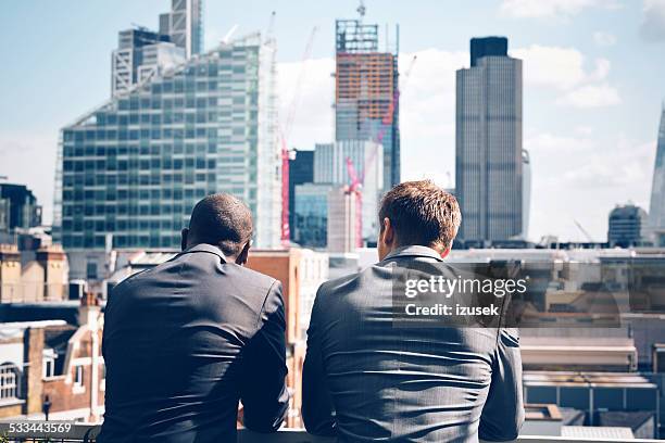 two businessmen looking at city scape - huizenmarkt stockfoto's en -beelden