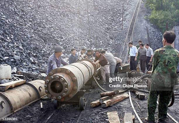 Workers install a pipeline to pump water from the Daxing Colliery where a flood trapped over 100 miners, August 9, 2005 in Xingning of Guangdong...