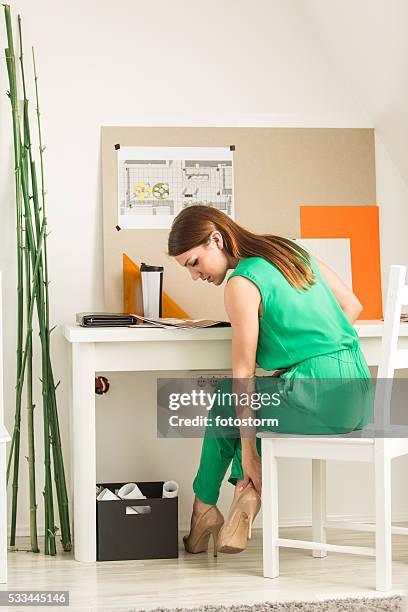 businesswoman massaging ankle at office desk - high heels pain stock pictures, royalty-free photos & images