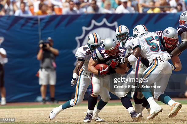 Marc Edwards of the New England Patriots struggles to hold on to the ball as he is being chased by Brian Walker and Morlon Greenwood of the Miami...