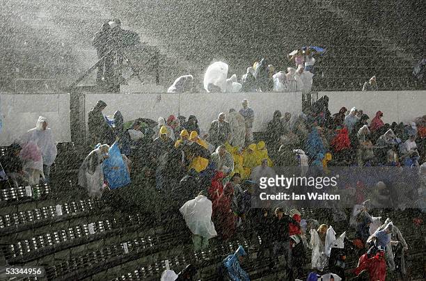 Spectators sit in the rain as they wait for the evening session to start during a rain delay at the 10th IAAF World Athletics Championships on August...