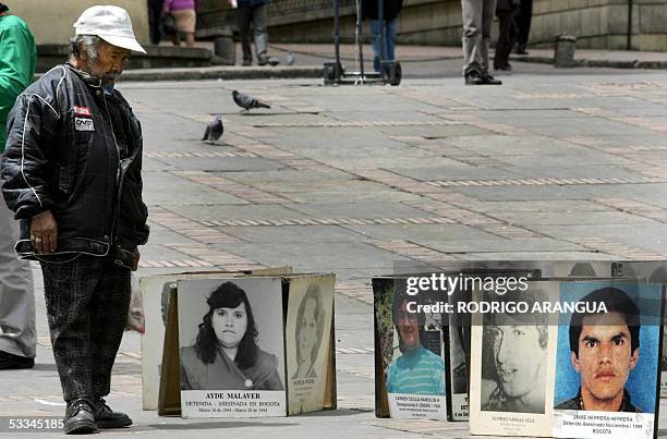 Una persona observa fotos de victimas de crimenes y violaciones de Derechos Humanos el 09 de agosto de 2005 en la Plaza Bolivar de Bogota, en...