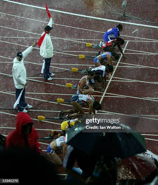 Athletes stand in the rain as they wait for the start of the women?s 100 metres Hurdles at the 10th IAAF World Athletics Championships on August 9,...