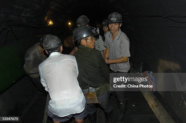 Workers install a pipeline to pump water from a pit at the Daxing Colliery where a flood trapped over 100 miners August 9, 2005 in Xingning of...