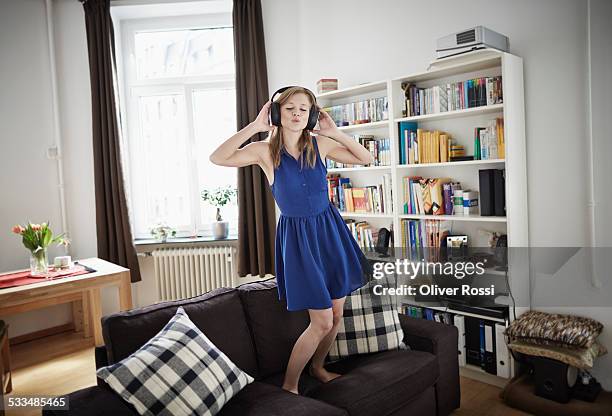 young woman at home listening to music - sleeveless dress stock pictures, royalty-free photos & images