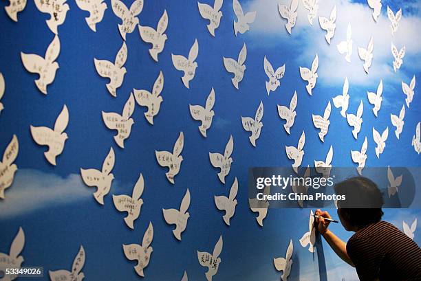 Visitor signs her name on a paper dove during an exhibition on the 1937 Nanjing Massacre at the National Museum August 10, 2005 in Beijing, China....