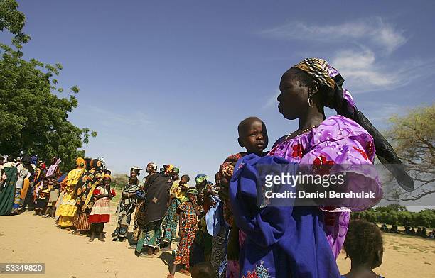 Hundreds of Nigerois women wait in line with their malnourished children whilst waiting to receive aid from the Save The Children Clinic in the...