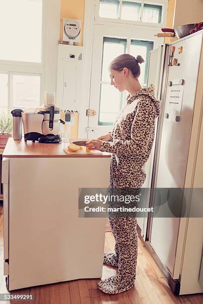 young woman in onesie using a juicer in small kitchen. - infant bodysuit stock pictures, royalty-free photos & images