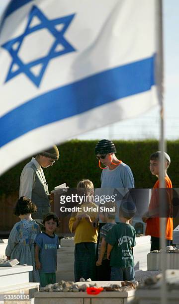 Jewish settler and her children recite prayers over graves August 10, 2005 at Neve Dekalim settlement in the Gaza Strip. Tensions are running high...