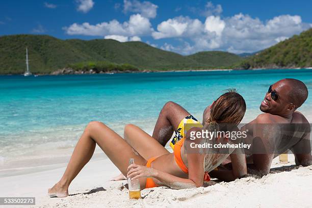 flitterwochen paar trinken bier am strand im hafen st.john, usvi - women tanning beach drink stock-fotos und bilder