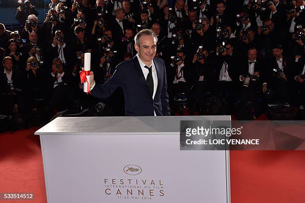 French director Olivier Assayas poses with his trophy during a photocall after he was awarded with the Best Director prize for the film "Personal...