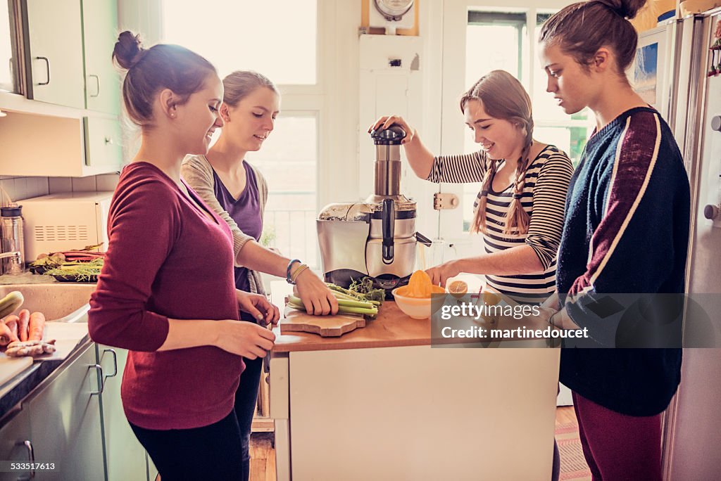 Four roommates using a juicer in their appartement kitchen.