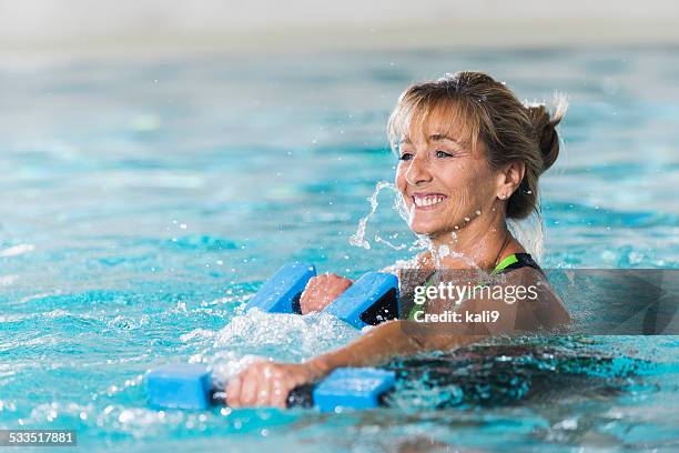 mature woman doing water aerobics with dumbbells - 女子水泳 個照片及圖片檔