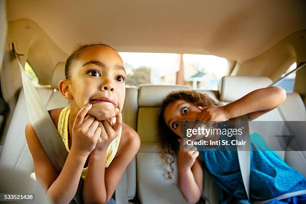 sisters (4-7) making funny faces in car - car back seat stock pictures, royalty-free photos & images