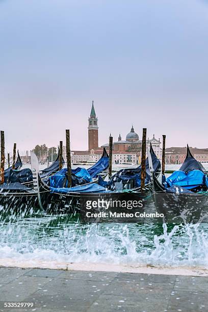 row of gondolas with acqua alta coming, venice - acqua splash ストックフォトと画像