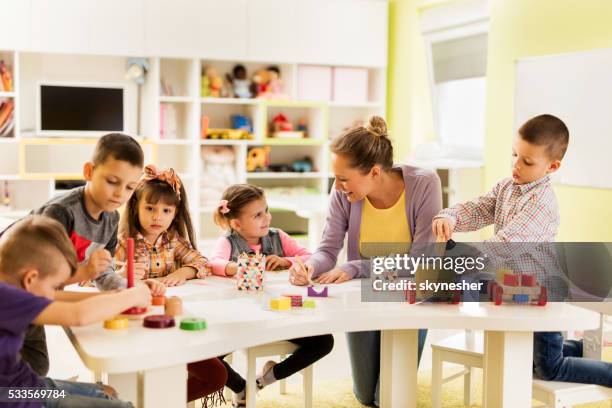 profesor feliz disfrutando con grupo de niños en edad preescolar. - preschool building fotografías e imágenes de stock