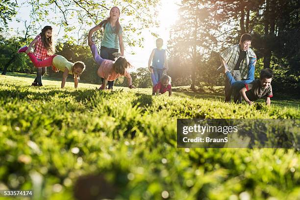 below view of playful children having fun in wheelbarrow race. - low angle view grass stock pictures, royalty-free photos & images