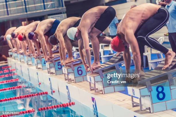 nadadores agachado no bloco de partida prontos para ir - swimming race imagens e fotografias de stock