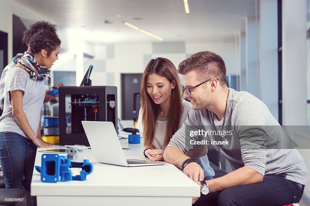 Coworkers working on laptop in 3d printer office