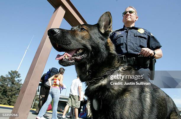 Bay Area Rapid Transit police officer Jason Ledford patrols with his bomb-sniffing dog Andy at the Oakland Coliseum station August 11, 2005 in...