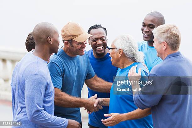 grupo multirracial de hombres, estrechándose las manos - african american man helping elderly fotografías e imágenes de stock