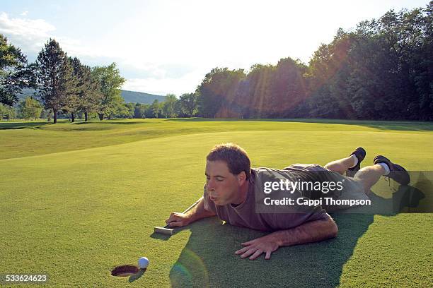golfer blowing air on golf ball - einlochen stock-fotos und bilder