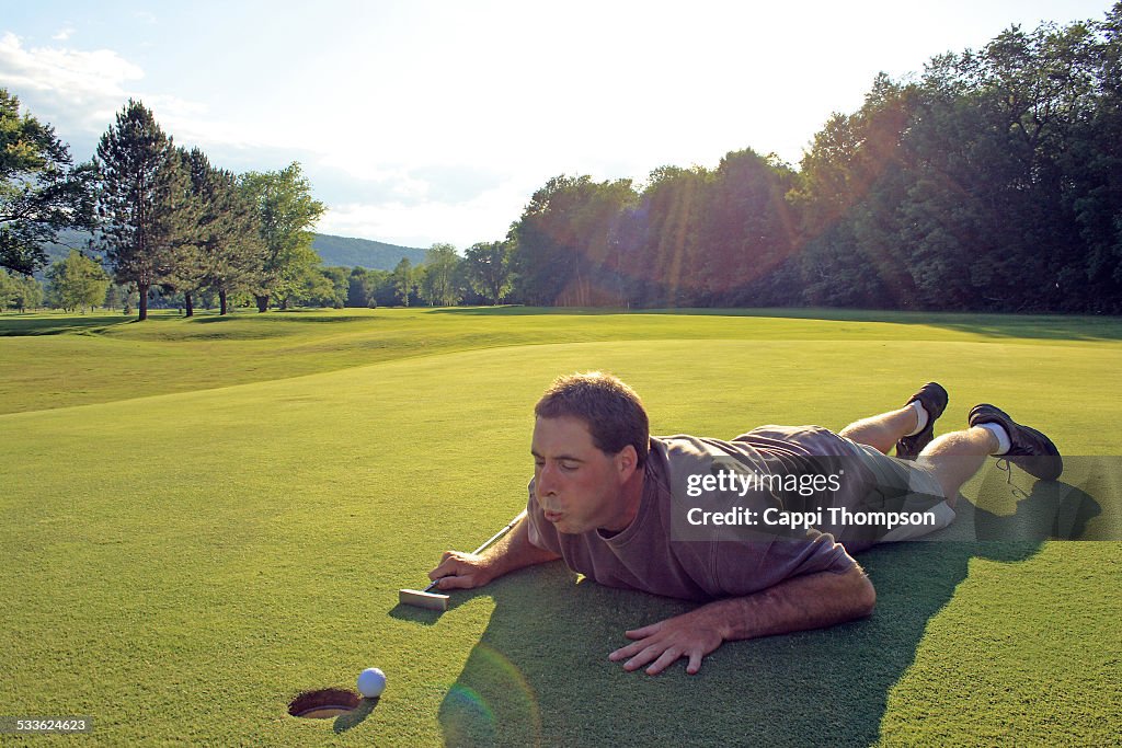 Golfer blowing air on golf ball