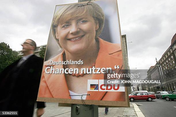 Man walks past an election poster featuring the Christian Democratic Union's leader and main candidate Angela Merkel in Berlin 11 August 2005....