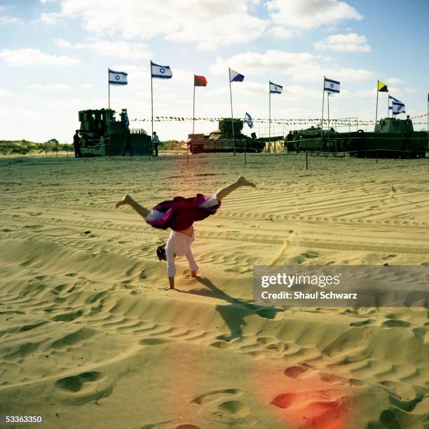 Young Israeli girl plays in the sand dunes as the army prepares a presentation of its tools for the Israeli independence day May 10, 2005 in the...