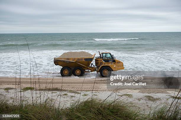 three axle articulated truck moving sand on eroded beach - reclamation stock pictures, royalty-free photos & images