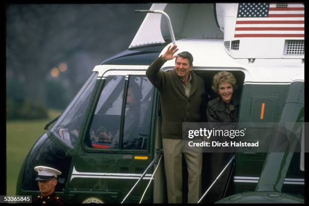 Casually clad President & Nancy Reagan waving before boarding Marine One helicopter, leaving WH for Camp David.