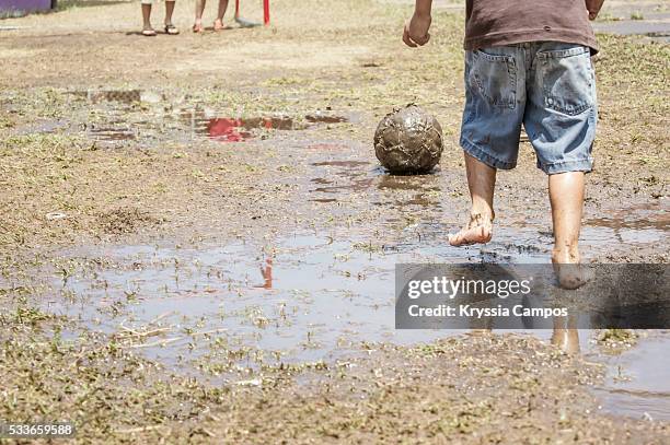 kid playing soccer in mud - barefeet soccer stock pictures, royalty-free photos & images