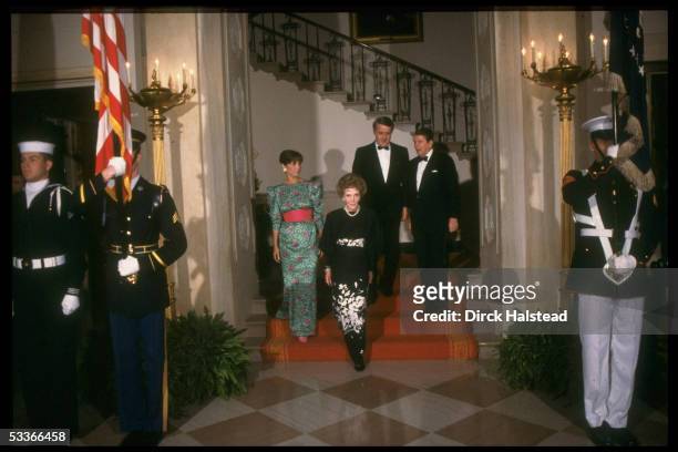 President Ronald Reagan & Nancy Reagan with Canadian PM & Mila Mulroney, men in black tie ladies in fancy gowns, descending red carpeted stairs,...