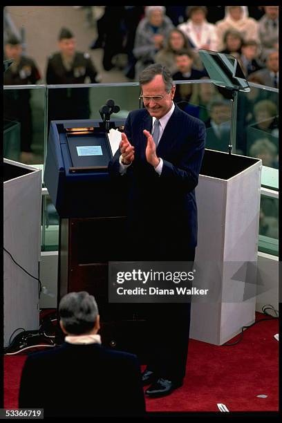 President Bush pausing at start of his inaugural address, turning to applaud President Reagan .