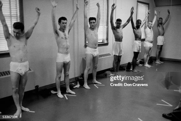 Wearing only underwear, singing star turned US Army Pvt. Elvis Presley raises his arms along with several other inductees during an inspection at Ft....