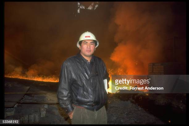 Beijing Bureau Chief Jaime Florcruz sporting hardhat, framed by fiery glow of molten metal at air polluting Benxi Steel mill.