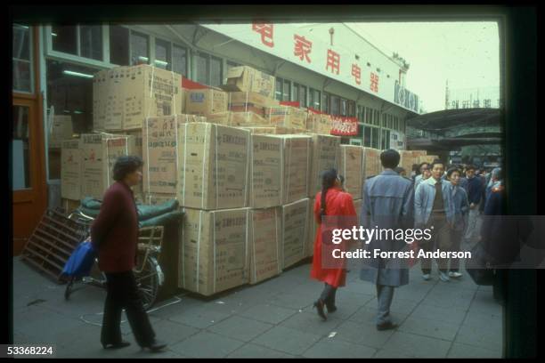 Boxed refrigerators & washing machines stacked outside appliance store, stockpiled in ample supply vs. Traditional scarcity of luxury goods.