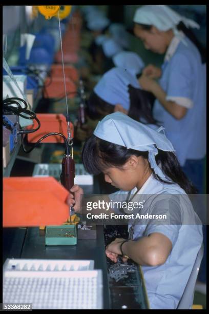 Women assembling cassette tape deck parts for export via Hong Kong, at Shinwa Industries Ltd. .