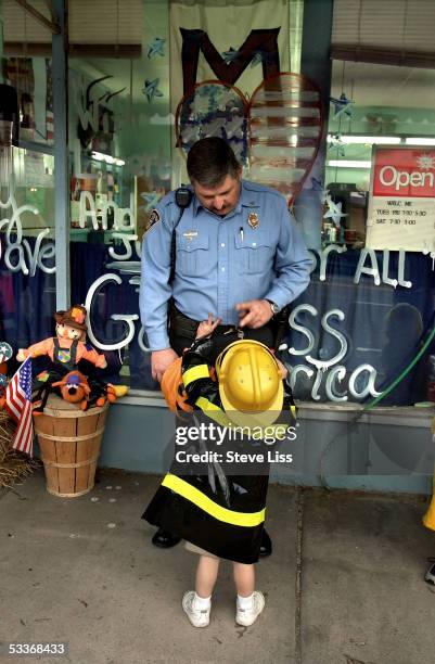 Police officer making friends with a little boy costumed as firefighter.