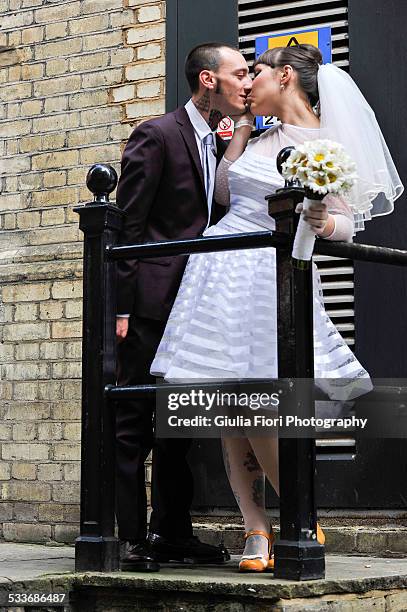 newlyweds kissing in the street - bouquet fiori stock-fotos und bilder