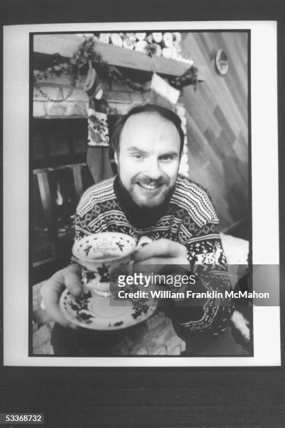 Author Tom Hegg holding up christmas tea cup based on his book CUP OF CHRISTMAS TEA at his home.