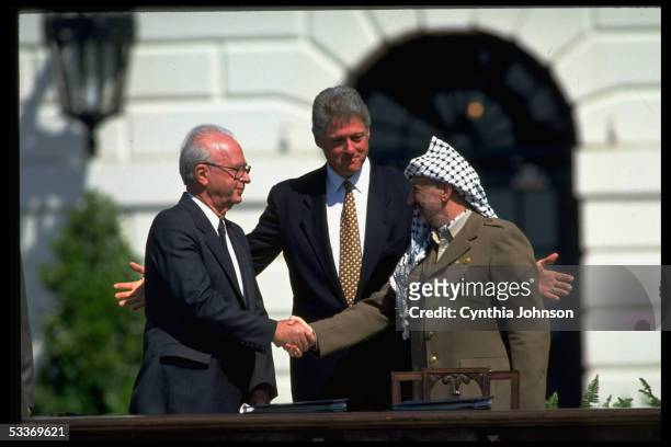 President Clinton smiling as PLO chairman Yasser Arafat & Israeli PM Itzak Rabin seal signing of Israel-PLO peace accord with historic handshake, at...