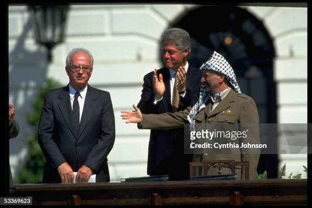 President Bill Clinton clapping as PLO chairman Yasser Arafat extends hand to an uncomfortable Israeli PM Yitzak Rabin during official signing of...