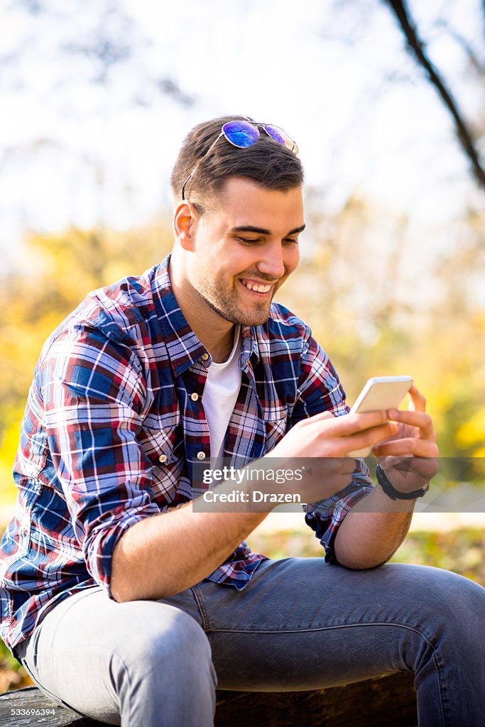 Portrait of young handsome man using smartphone outdoors