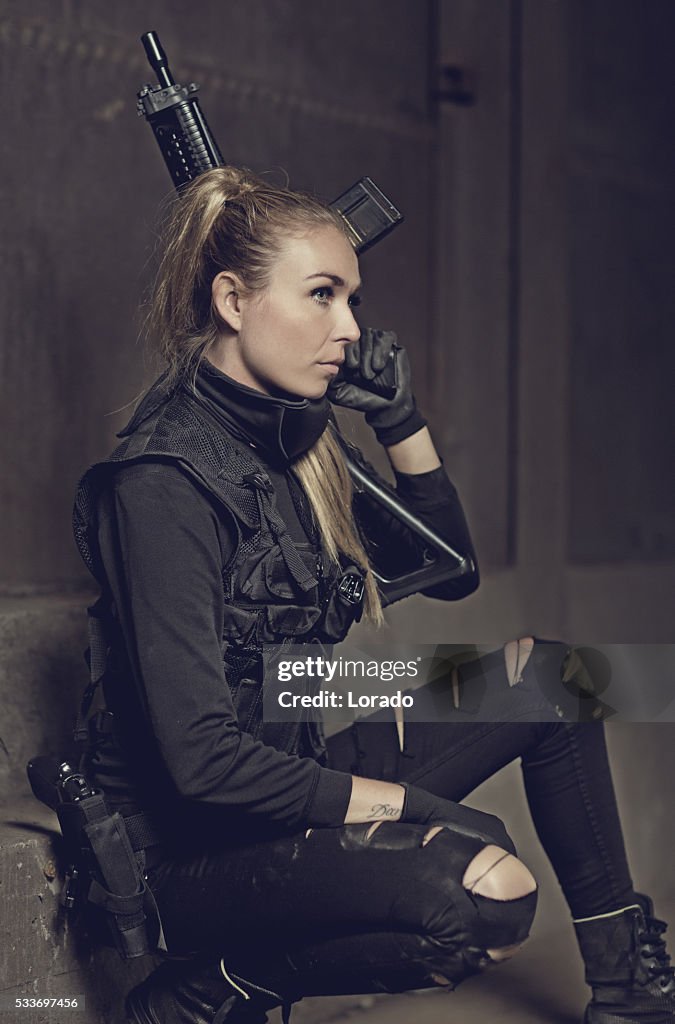 Female military swat team member holding rifle in abandoned warehouse