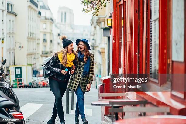 two girls having a walk on the streets of paris - paris autumn stock pictures, royalty-free photos & images