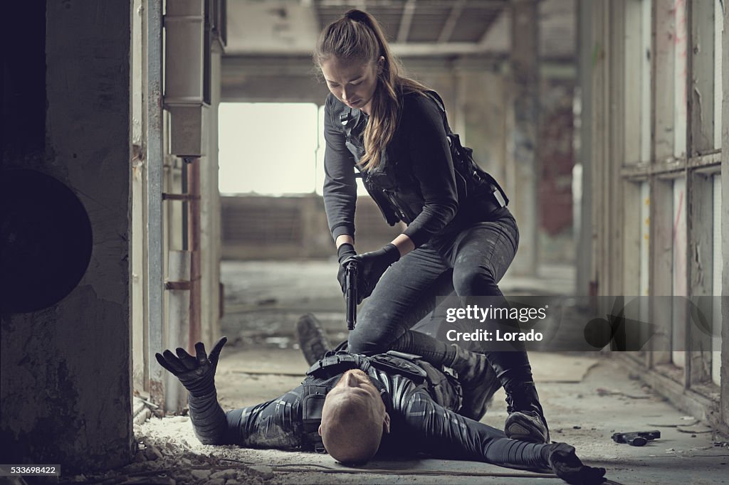 Female swat team member arresting male insurgent at gunpoint