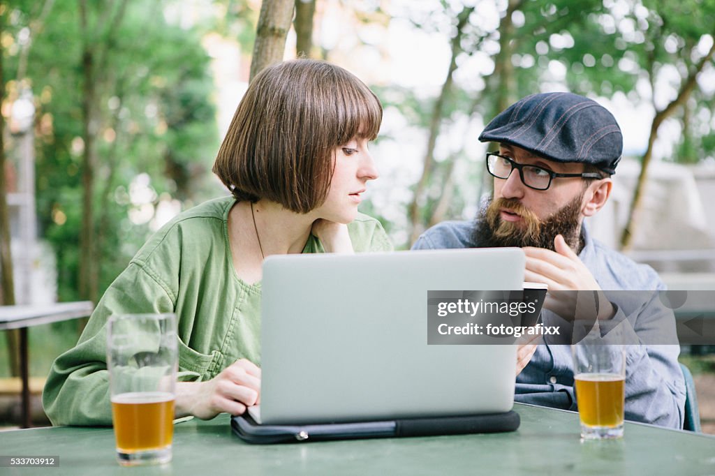 Hipster barbudo e namorada no Jardim da Cerveja trabalho no computador portátil