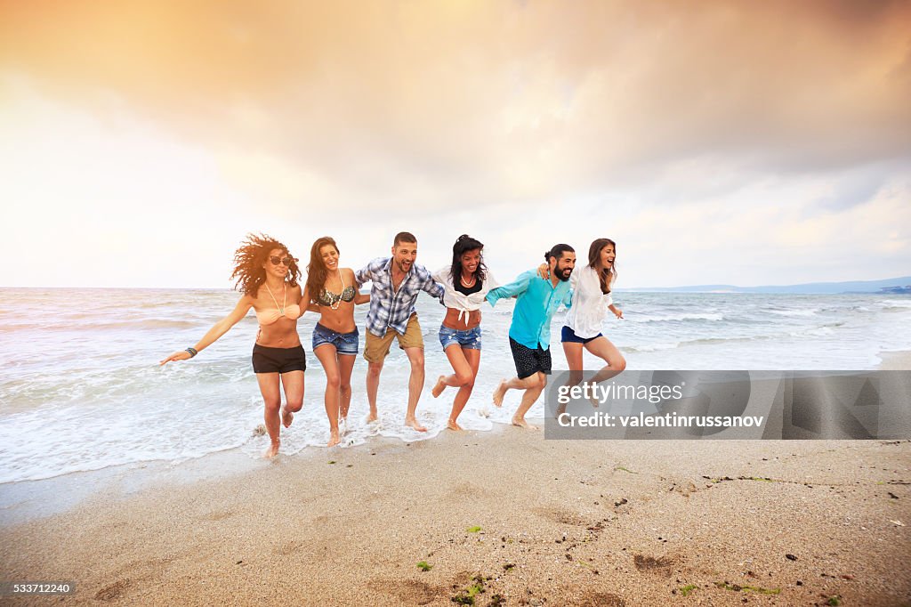 Friends running on the beach-hand to hand